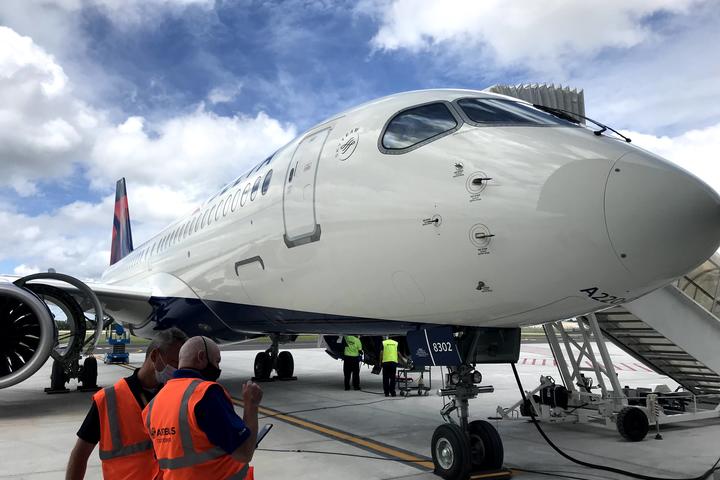 A220-300 parked on tarmac with stair truck and employees